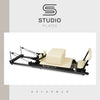 Studio Pilates reformer machine with 'Studio Pilates' branding on a light gray background