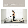 Woman using a Pilates reformer machine with 'Studio Pilates' branding.