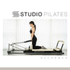 Woman using a Pilates reformer machine with Studio Pilates branding.