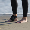 Person wearing black ankle support on a beach