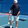 Person holding a pickleball paddle and ball on a blue pickleball court